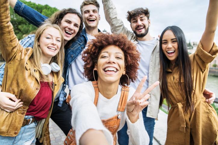 Group of happy friends taking selfie outside