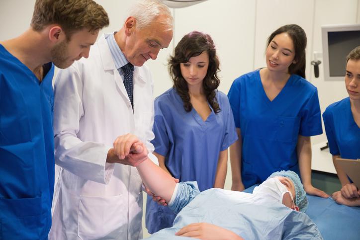 Medical students and professor checking pulse of student