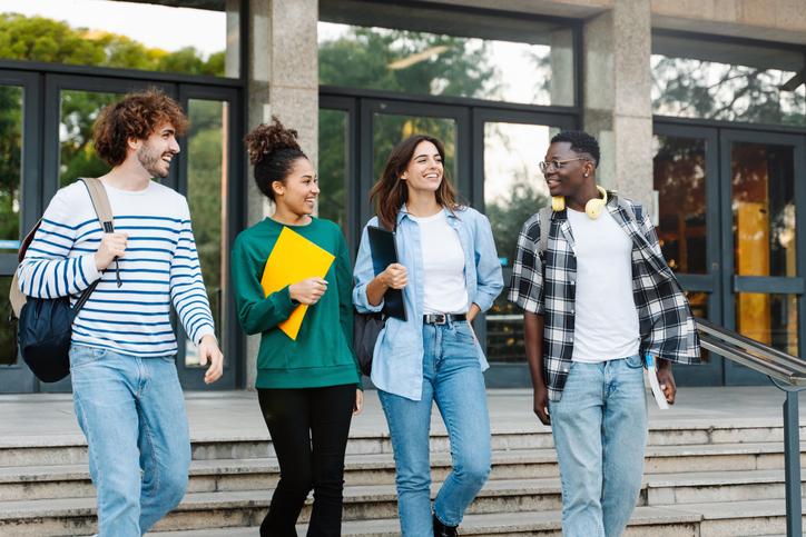 Multi ethnic group of Latin and African American college student friends walking outside University building