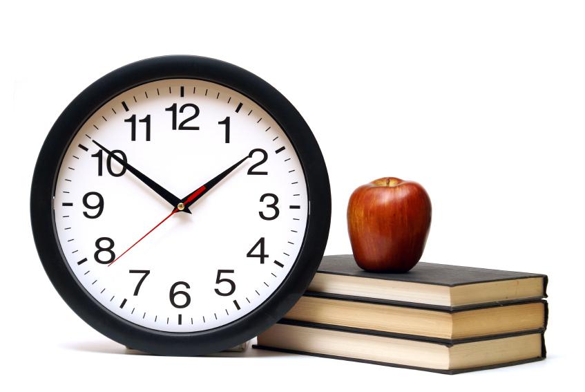 Clocks next to pile of books with apple