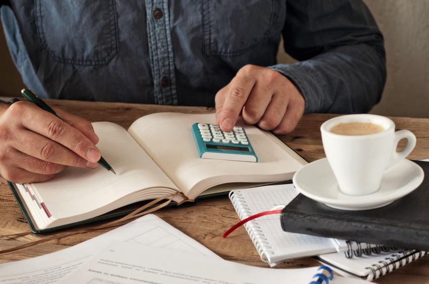 Man writing in a diary with calculator