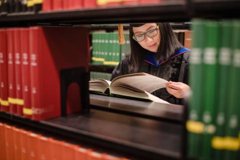 PhD student reading a book in the library 