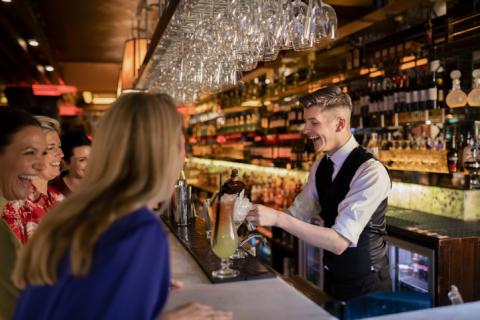 Young man bartending with female customers