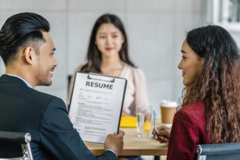 Man and woman interviewing a young woman and holding her CV/iStock