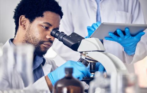 scientist looking through microscope