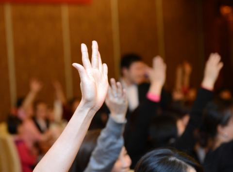 Students putting hands up in lecture theatre